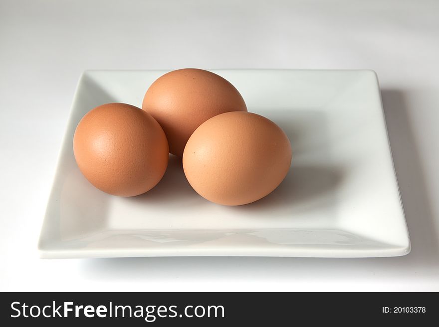 Three brown bio eggs on a square plate. Three brown bio eggs on a square plate