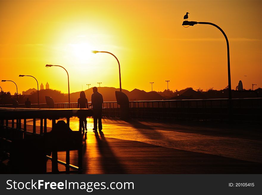 Couple walking on the boardwalk at sunset. Couple walking on the boardwalk at sunset