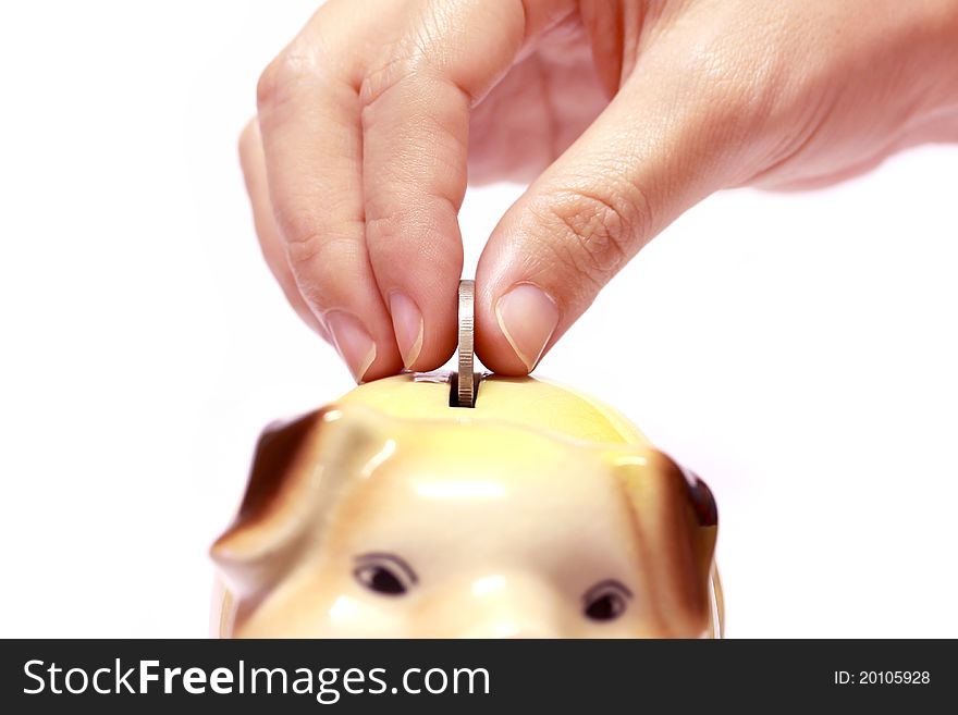 Female hand with coin and a piggy bank isolated against a white background