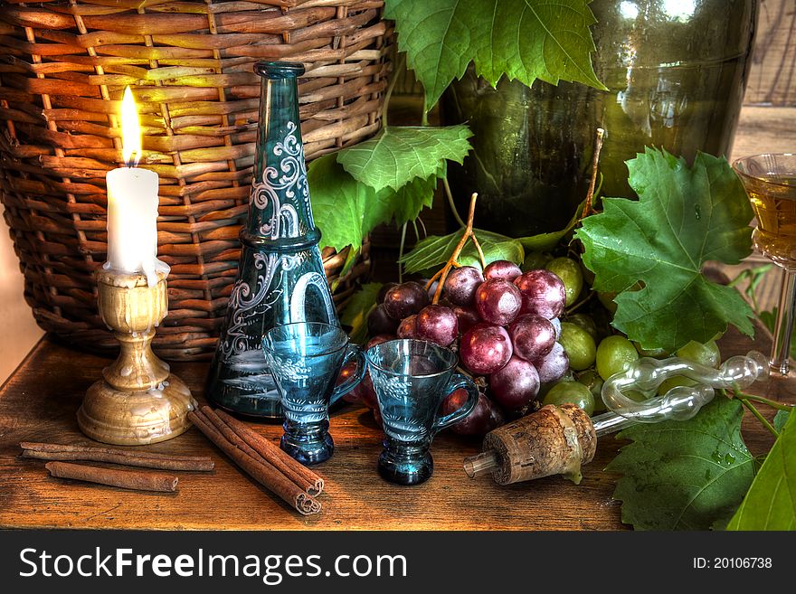 Wine,grapevine,grapes,old decanter with glasses,candlelight and wicker basket on background. Wine,grapevine,grapes,old decanter with glasses,candlelight and wicker basket on background.