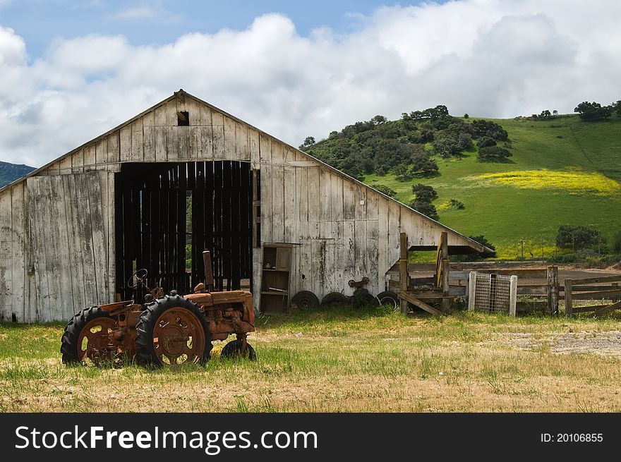 Old wooden barn with rusted tractor sitting out front.