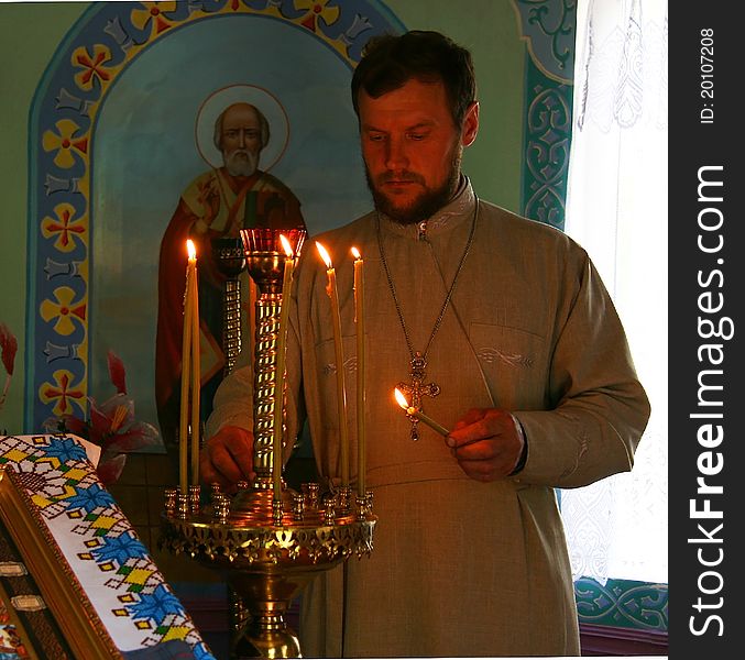 Orthodox priest lights a candle in the church. Orthodox priest lights a candle in the church