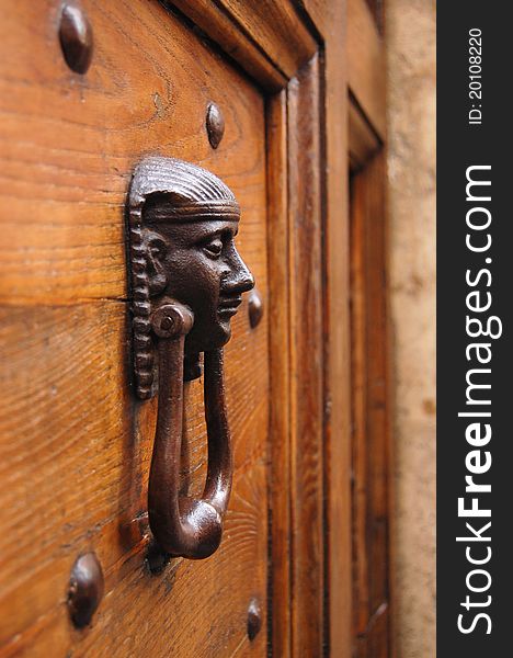 Close-up of the Egyptian human head door knocker in Rome. Bright wooden door. Close-up of the Egyptian human head door knocker in Rome. Bright wooden door