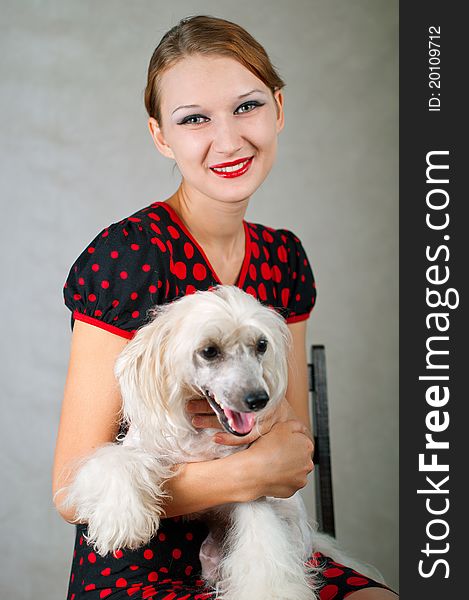 The beautiful girl and chinese crested dog on grey background. Shallow DOF, focus on the girl