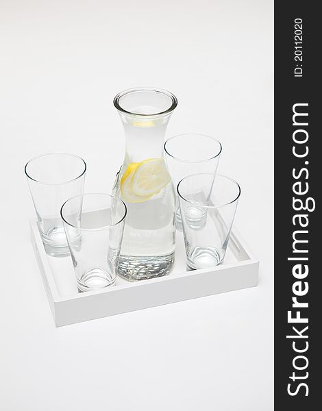 Carafe of lemon water and four glasses - portrait interior. Carafe of lemon water and four glasses - portrait interior.