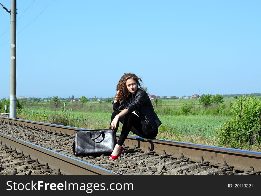 A girl sits on the rail waiting for the train. A girl sits on the rail waiting for the train