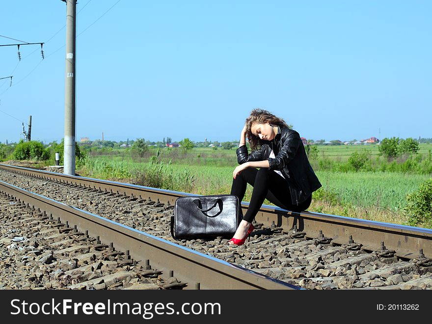 A girl sits on the rail waiting for the train. A girl sits on the rail waiting for the train