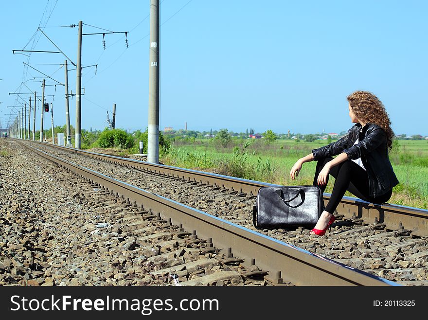 A girl sits on the rail waiting for the train. A girl sits on the rail waiting for the train