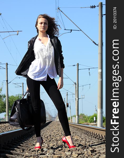 A girl sits on the rail waiting for the train. A girl sits on the rail waiting for the train