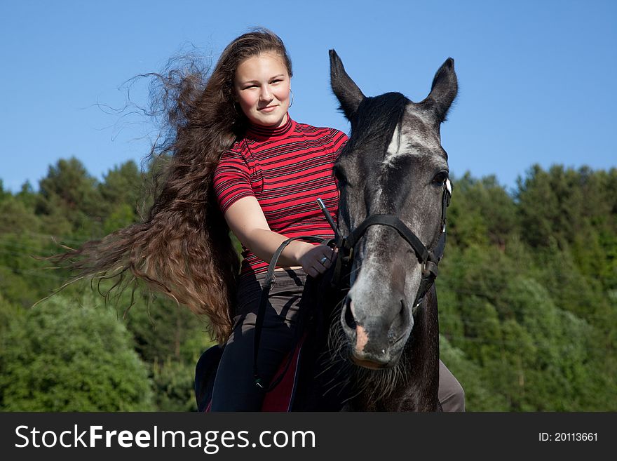 Beautiful girl with brown hair on a black horse