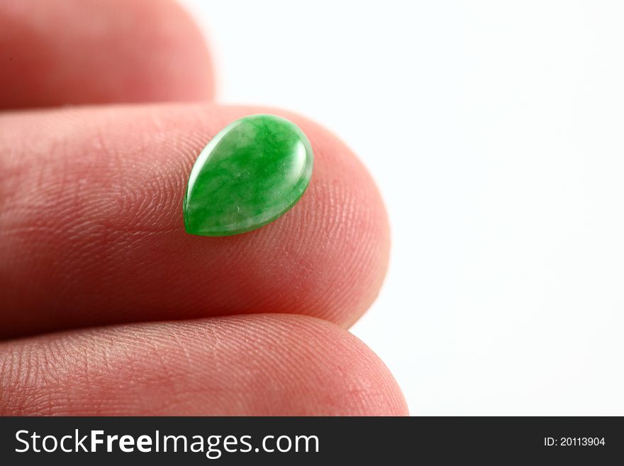 A greenish droplet-shaped type A jade / jadeite beads placed on finger top towards a white background. Type A means it has not been treated in any way except surface waxing. A greenish droplet-shaped type A jade / jadeite beads placed on finger top towards a white background. Type A means it has not been treated in any way except surface waxing.