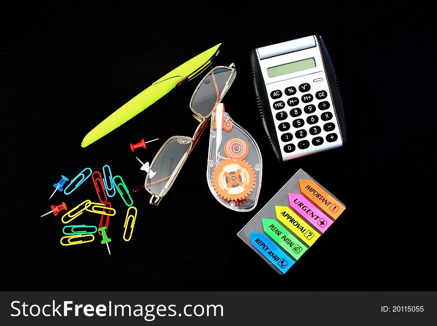 Colored office tools on a black desk