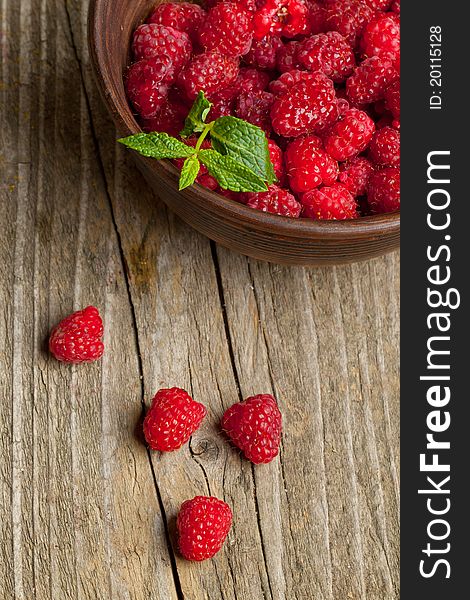 Bowl of fresh ripe raspberries and mint's leafs on old wooden table