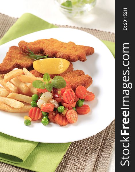 Fried fish served with French fries and mixed vegetables. Fried fish served with French fries and mixed vegetables