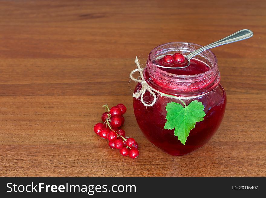 Glass pot of currant jam over wooden table