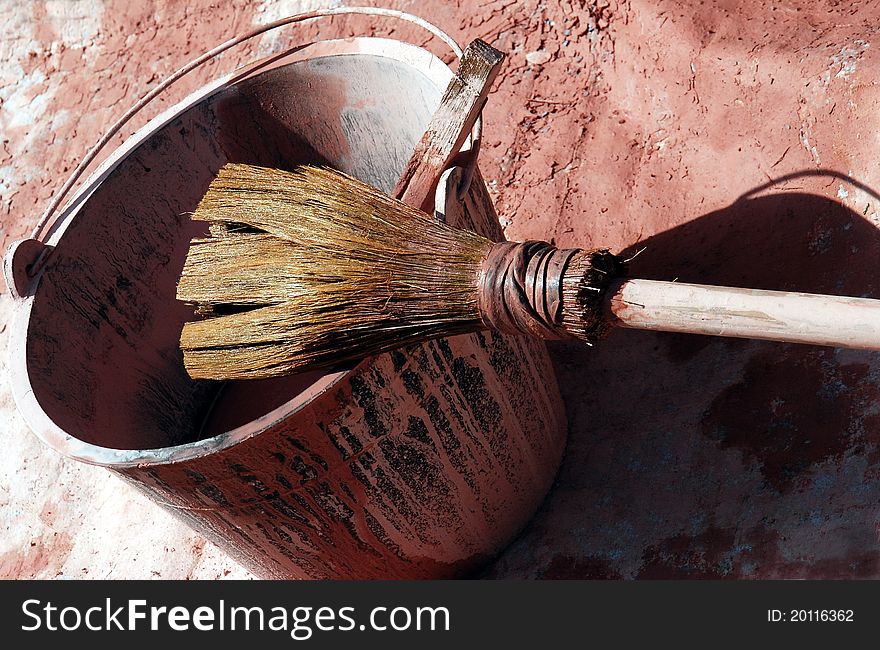 A large paintbrush with a paint bucket. A large paintbrush with a paint bucket