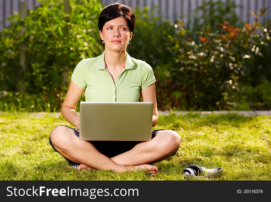 Caucasian woman is sitting on the grass with laptop. Caucasian woman is sitting on the grass with laptop