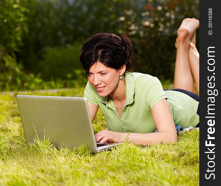 Caucasian woman is sitting on the grass with laptop. Caucasian woman is sitting on the grass with laptop