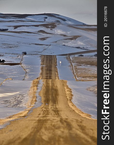 Sunset winter in the Prairie with gravel road and hills