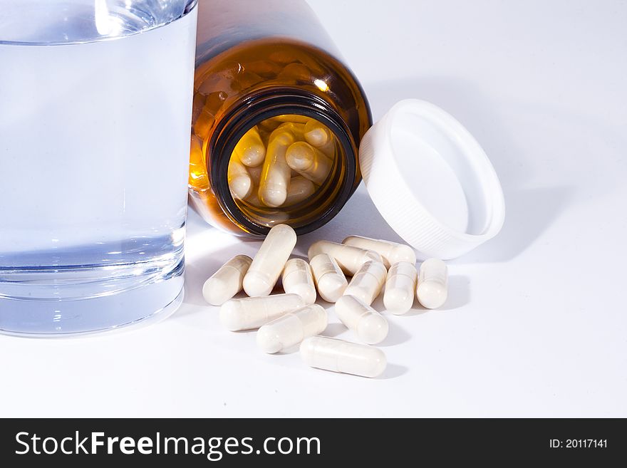 Bottle of pills with a glass of water on white background. Bottle of pills with a glass of water on white background