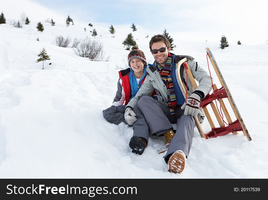 Young Father And Son In Snow With Sled