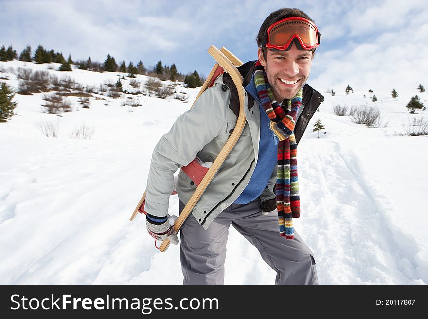 Young Man Carrying Sled In Alpine Landscape