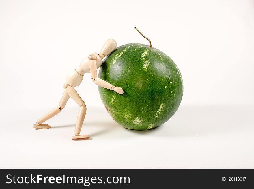 Overloaded wooden mannequin carrying a watermelon. Overloaded wooden mannequin carrying a watermelon