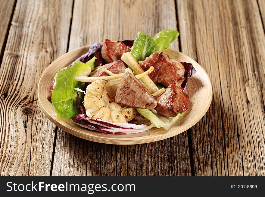 Pieces of pan fried pork on bed of vegetable salad. Pieces of pan fried pork on bed of vegetable salad