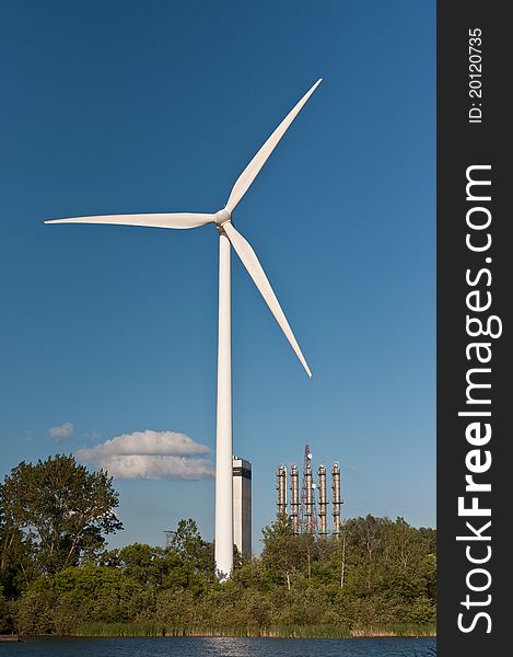 Large Wind Turbine with Trees and Blue Sky
