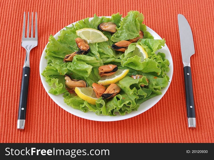 Salad with mussels and lemon on a plate