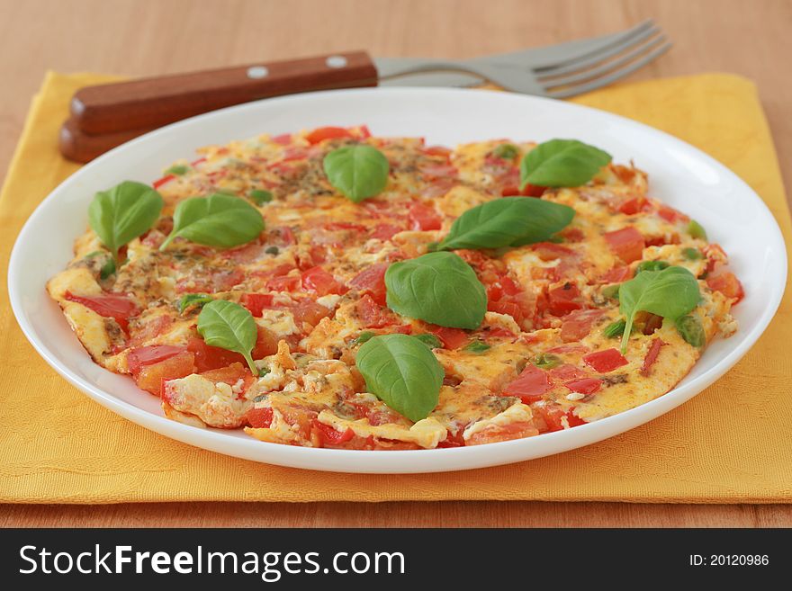 Omelet with vegetables and basil on an white plate