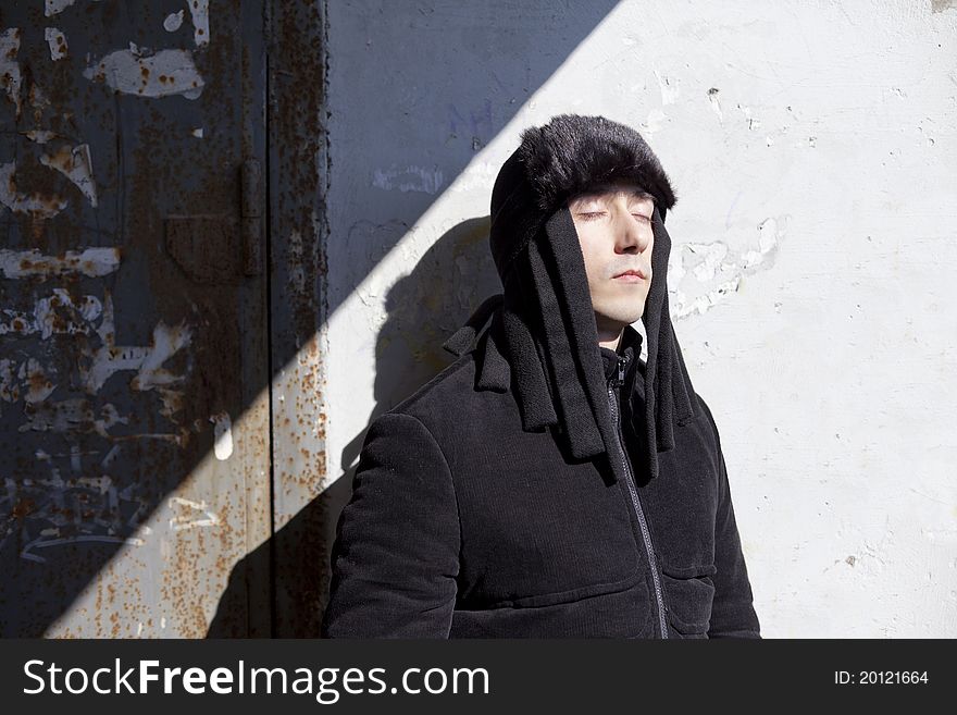 Young man closed eyes near wall