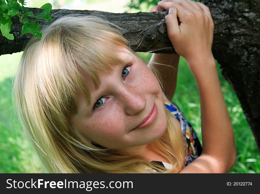 The young girl with freckles have fun near tree