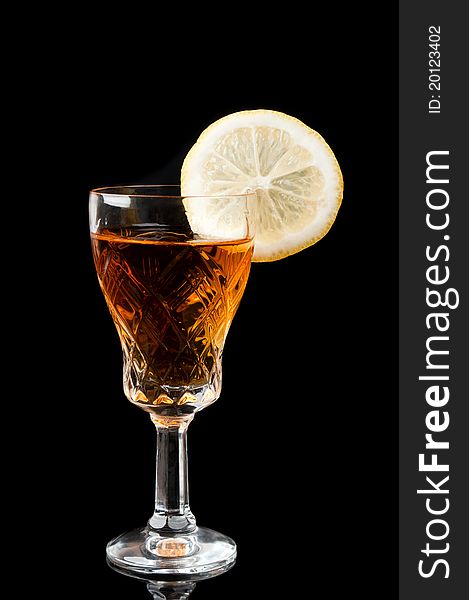 Glass of cognac with lemon isolated on a black background