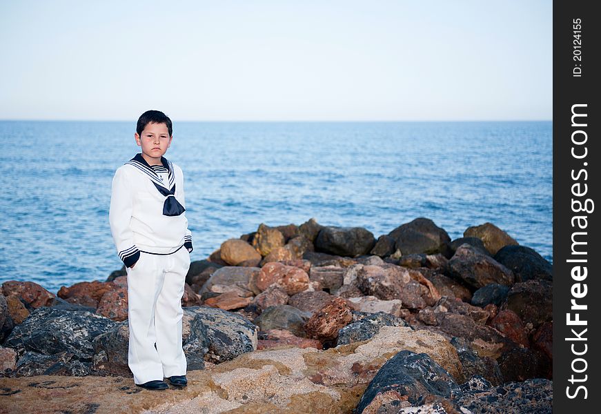 Boy in a sailor suit standing on the beach