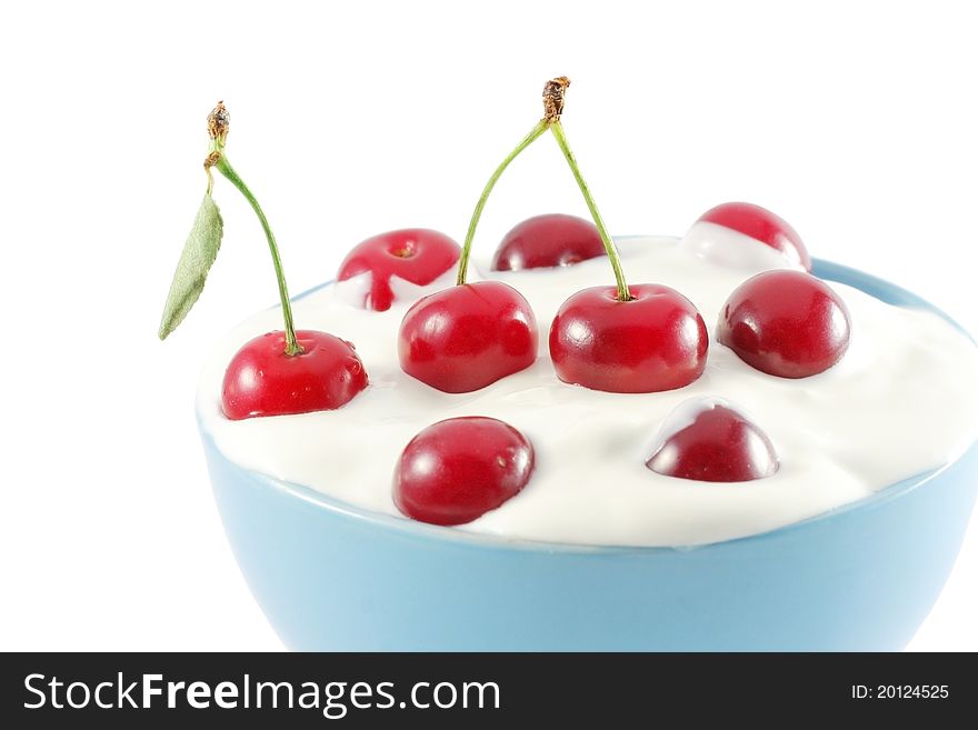 Blue bowl full of red cherries in white cream isolated on white. Blue bowl full of red cherries in white cream isolated on white