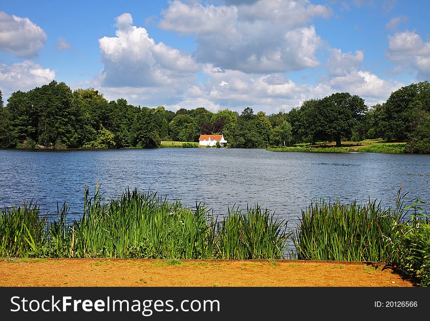 Whitewashed Lakeside House in Virginia Water England with puffy Cumulonimbus clouds. Whitewashed Lakeside House in Virginia Water England with puffy Cumulonimbus clouds