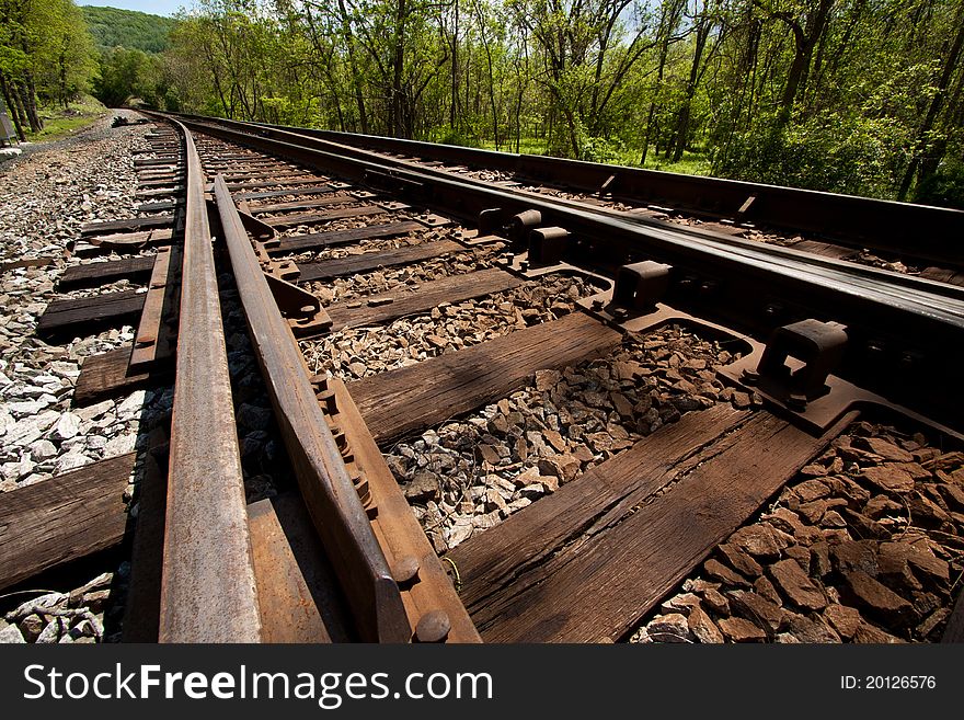 An angled view down railroad tracks in a country setting. An angled view down railroad tracks in a country setting.