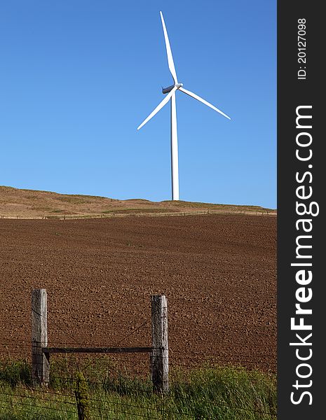 A wind turbine stands alone in a farm field. A wind turbine stands alone in a farm field.