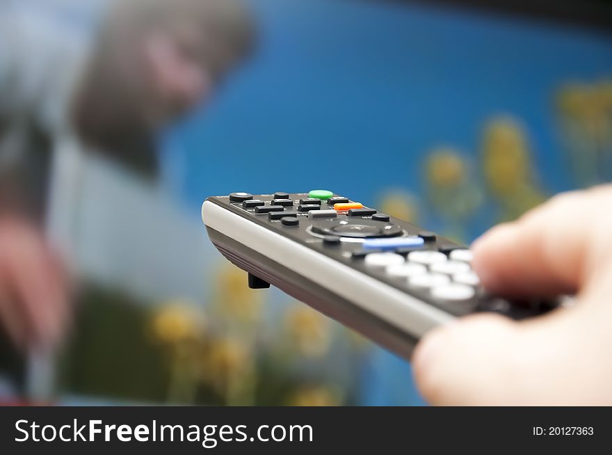 Hand holding TV remote control towards a tv screen. Hand holding TV remote control towards a tv screen.