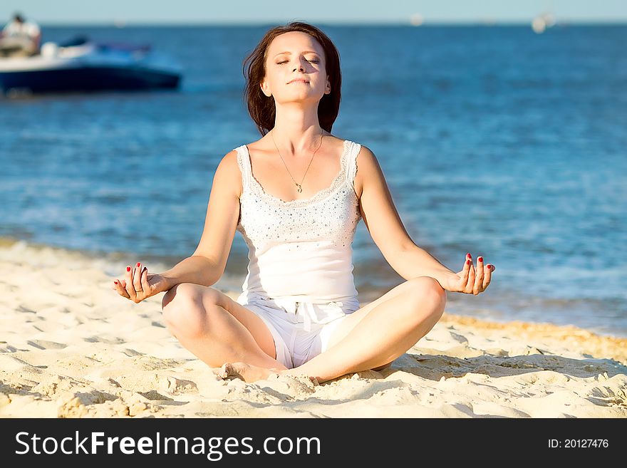 Young beautiful woman during yoga on sea beach