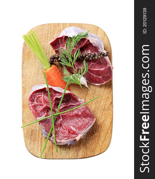 Raw shin beef, vegetable and herbs  on a cutting board - cut out on white