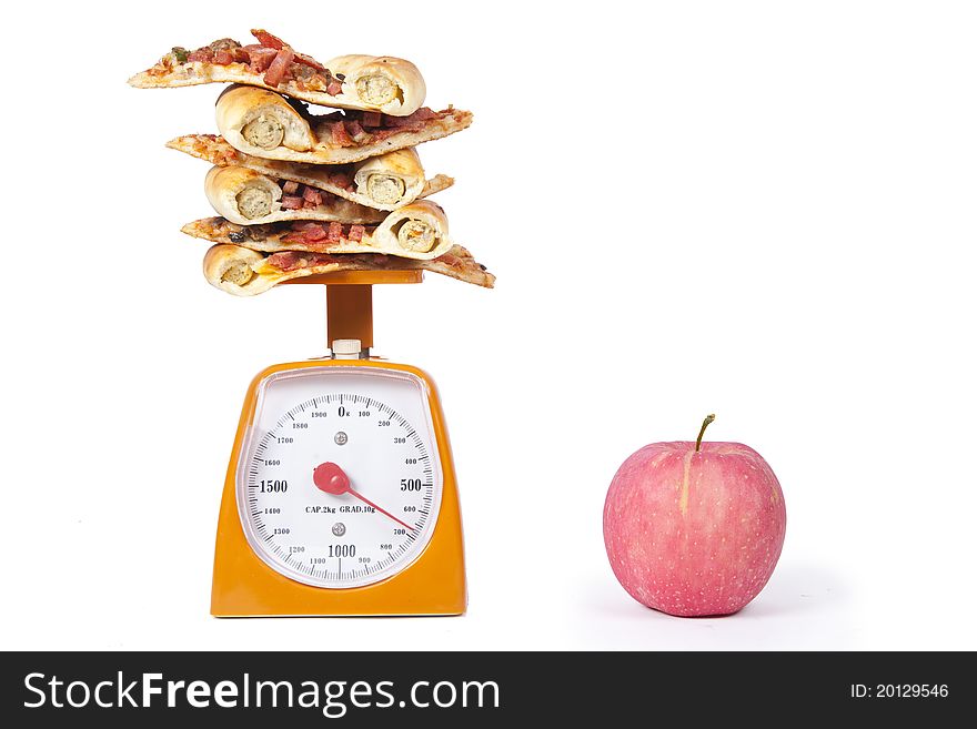 Photo of pizza slices stacked on a scale with an apple isolated over white. Photo of pizza slices stacked on a scale with an apple isolated over white