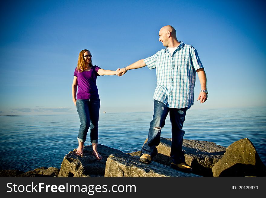 A couple standing on rocks holding hands. A couple standing on rocks holding hands.