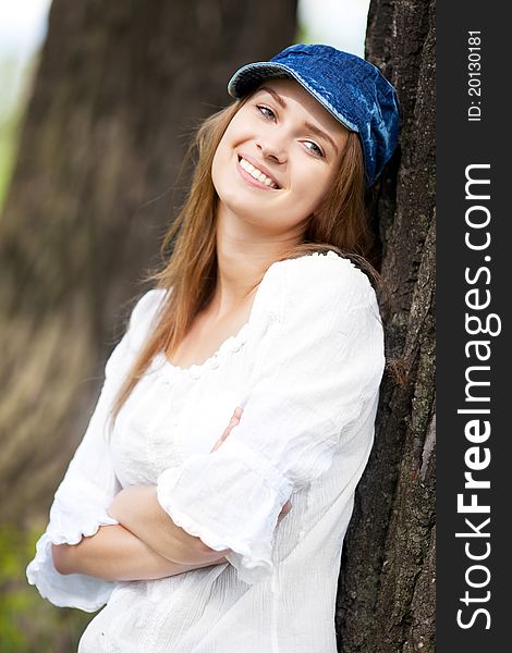 Happy young woman wearing a cap in the park on a warm summer day. Happy young woman wearing a cap in the park on a warm summer day