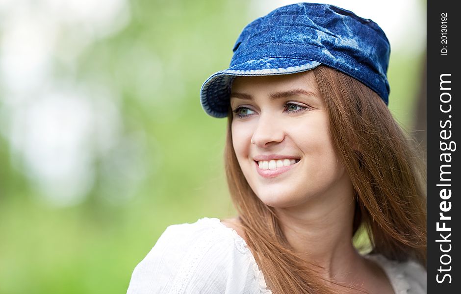 Happy young woman wearing a  cap in the park  on a warm summer day. Happy young woman wearing a  cap in the park  on a warm summer day