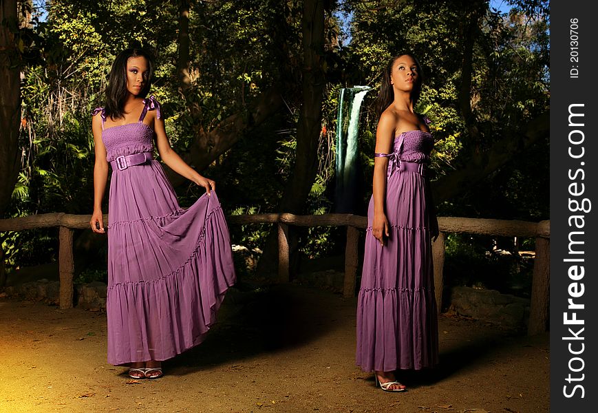 Fashion portrait portraying double exposure of a beautiful young fashion model in purple dress against natural background