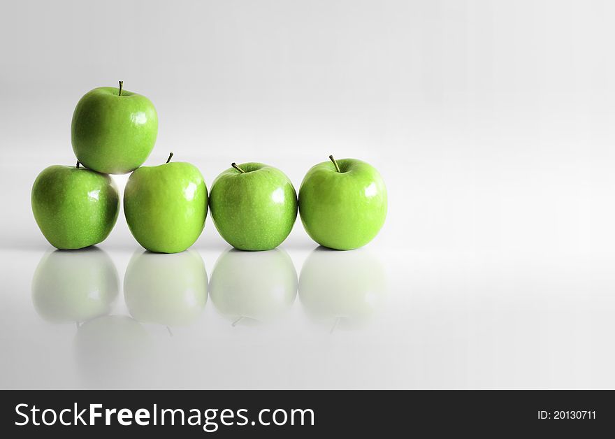 Five shiny green apples in empty white reflective space. Five shiny green apples in empty white reflective space