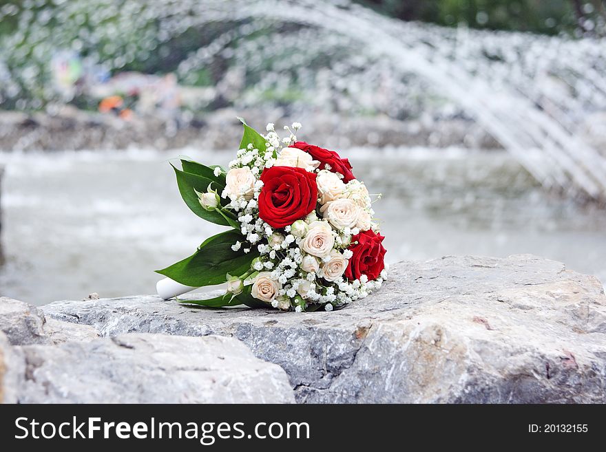 The beautiful beige bouquet of the bride lays on a fountain parapet