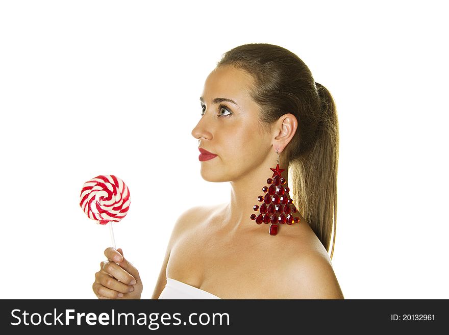 Close-up of a beautiful young woman with a lollipop and big earrings made ??of precious red stone in the form of a Christmas tree. Isolated. Close-up of a beautiful young woman with a lollipop and big earrings made ??of precious red stone in the form of a Christmas tree. Isolated